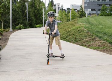 A child riding a Powerwing on the sidewalk