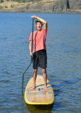 Shane on a paddle board holding a Straight Paddle